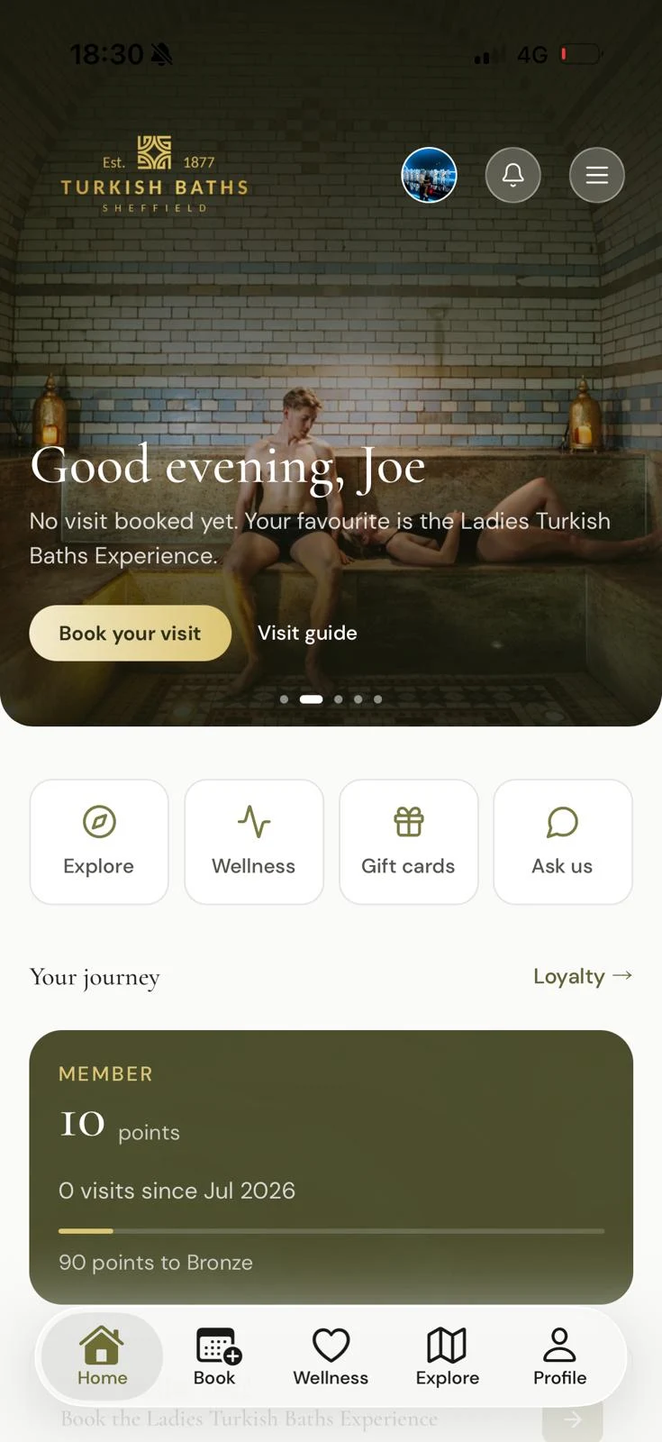 The Turkish Baths 1877 app's home screen: a welcome over the steam room, quick links to explore, wellness, gift cards and chat, and loyalty points.